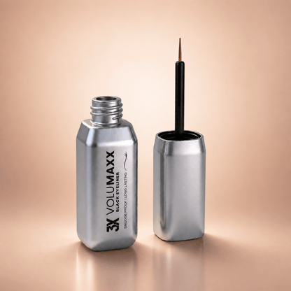 Silver waterproof liquid eyeliner bottle with brush on a beige background