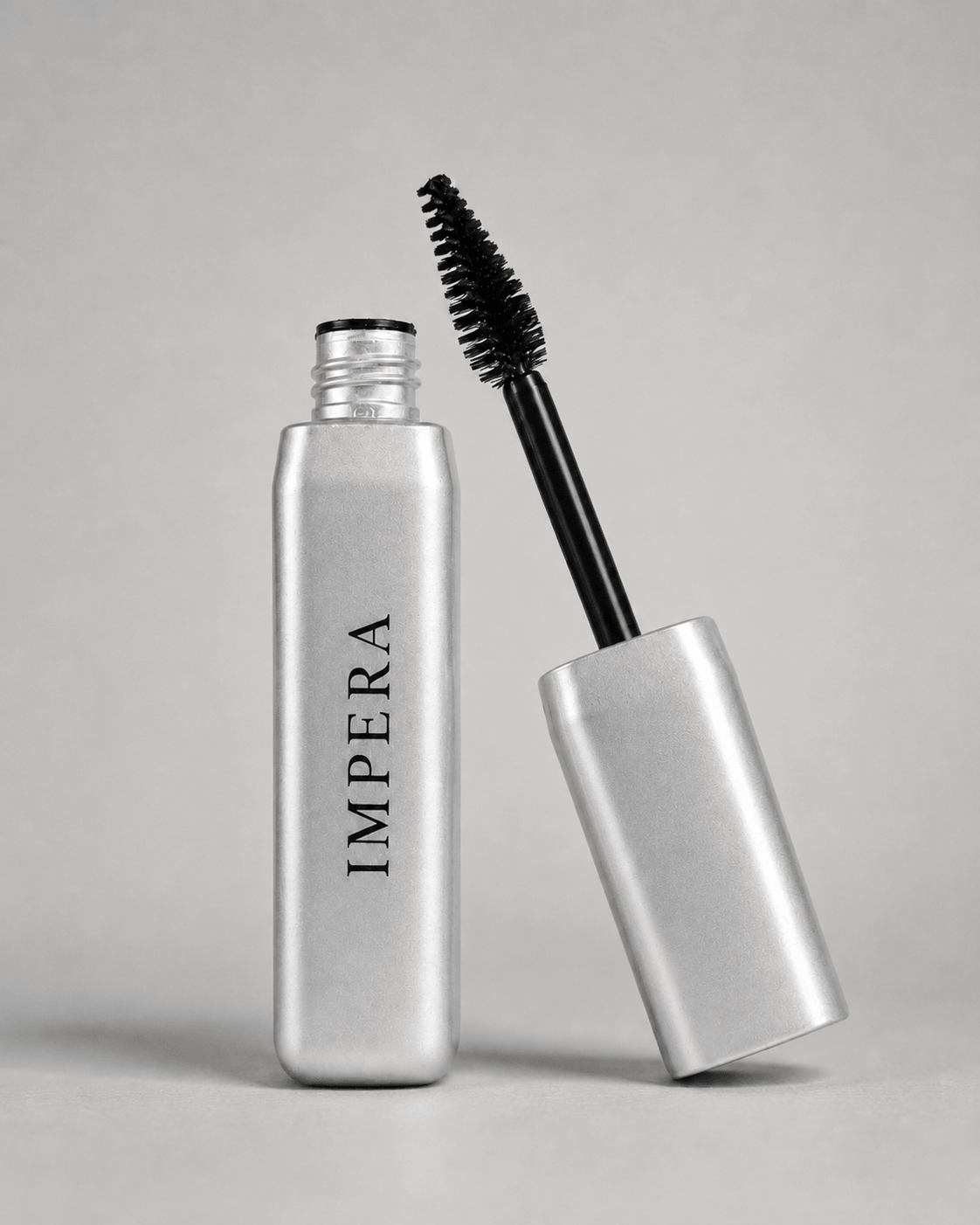 Silver volumizing mascara bottle with black wand on a gray background, featuring the brand 'IMPERA'.